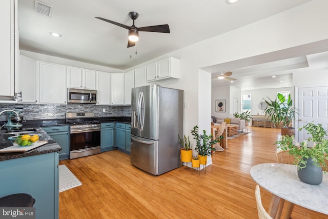 kitchen with ceiling fan, dark countertops, a sink, stainless steel appliances, and light wood-style flooring
