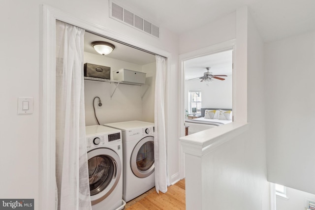 washroom featuring laundry area, a ceiling fan, visible vents, washing machine and dryer, and light wood finished floors