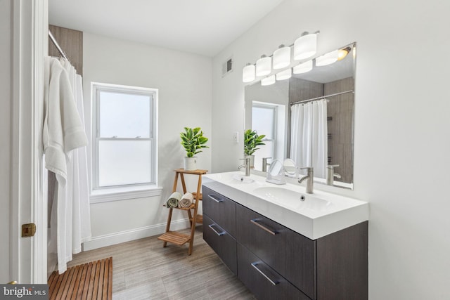 bathroom with baseboards, visible vents, a healthy amount of sunlight, and a sink