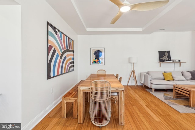 dining space with visible vents, a raised ceiling, ceiling fan, and wood finished floors