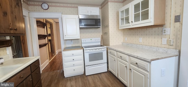 209 N Pine St, Seaford, DE 19973 - kitchen with wallpapered walls, stainless steel microwave, white range with electric stovetop, dark wood-style floors, and white cabinetry
