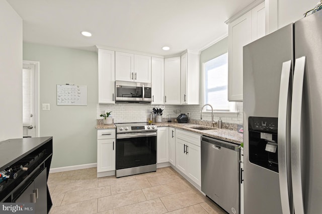 kitchen featuring appliances with stainless steel finishes, decorative backsplash, a sink, and white cabinets