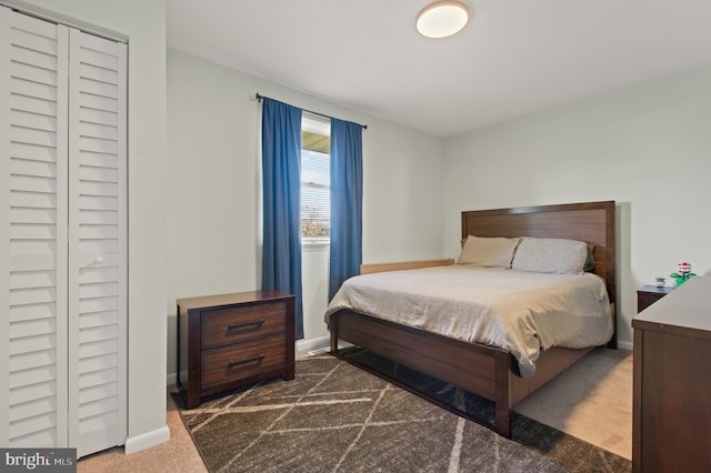 carpeted bedroom featuring a closet and baseboards