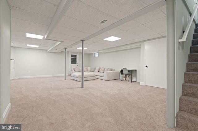 finished below grade area with a paneled ceiling, baseboards, carpet floors, stairs, and visible vents