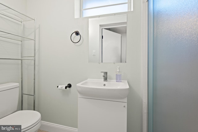 bathroom with toilet, vanity, and baseboards