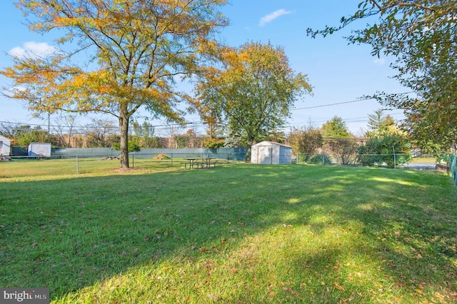 view of yard featuring an outbuilding, fence, and a shed
