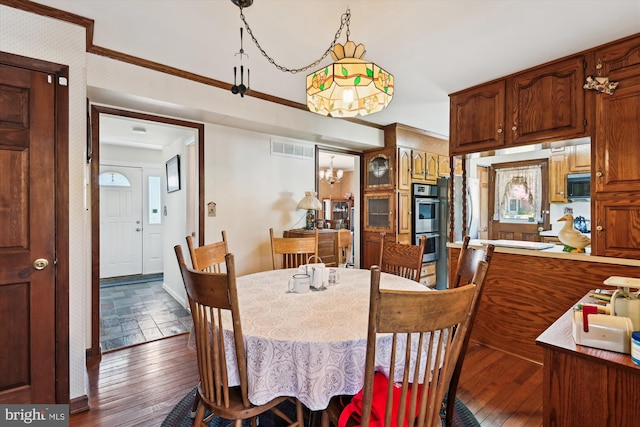 dining space with wood-type flooring, a chandelier, and visible vents