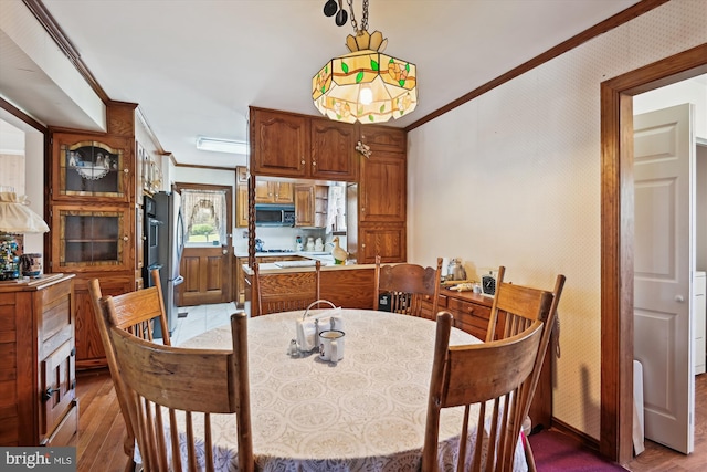 dining area with light wood-style flooring, baseboards, and ornamental molding