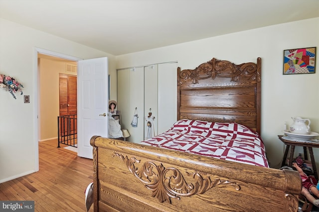bedroom with a closet, hardwood / wood-style floors, visible vents, and baseboards