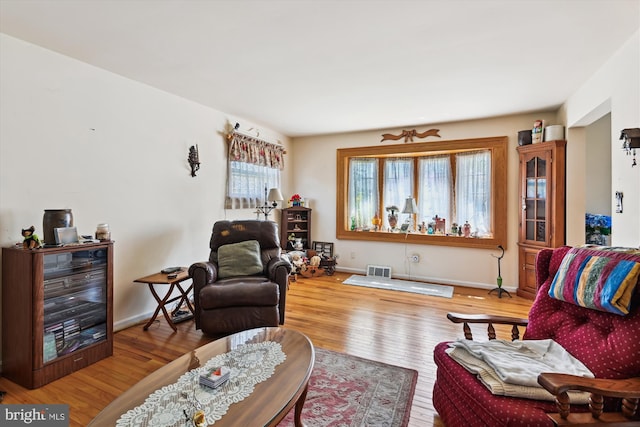 living room featuring visible vents, baseboards, and wood finished floors