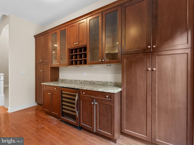 bar featuring light wood finished floors, wine cooler, and baseboards