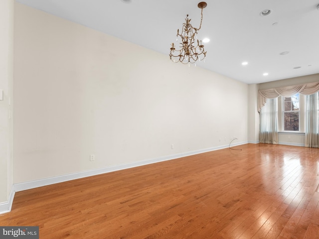 empty room featuring recessed lighting, baseboards, a chandelier, and light wood-style floors