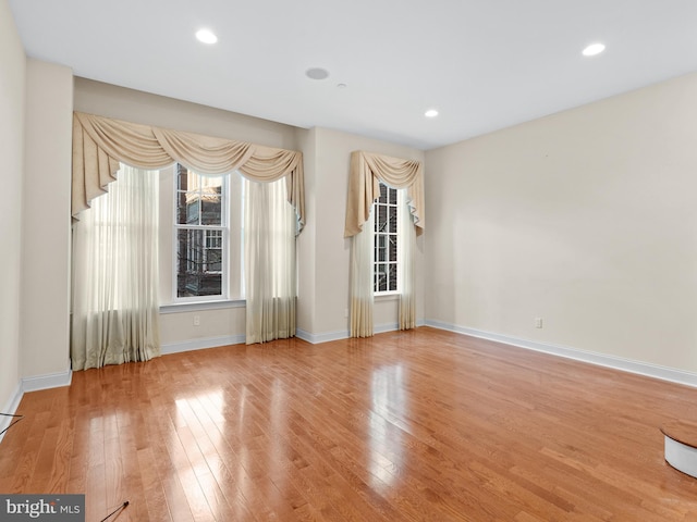 spare room with baseboards, wood finished floors, and recessed lighting
