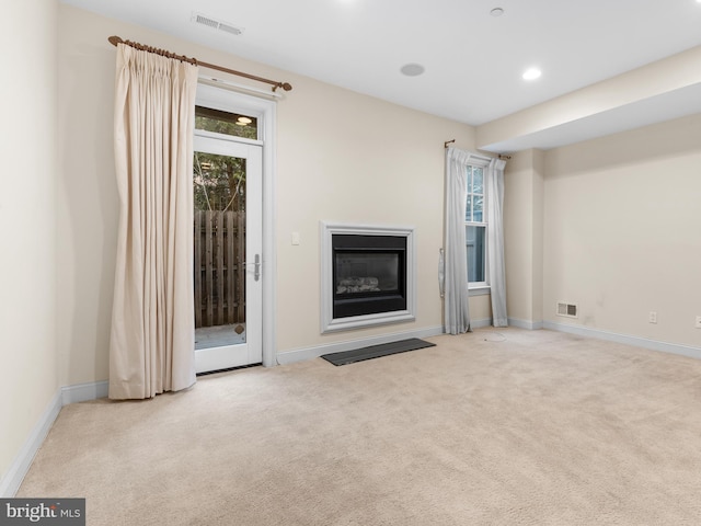 unfurnished living room with baseboards, visible vents, and carpet