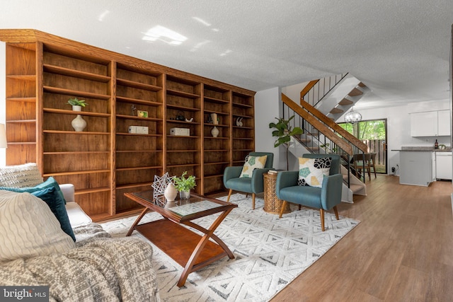 living room featuring stairs, a textured ceiling, built in features, and light wood-type flooring