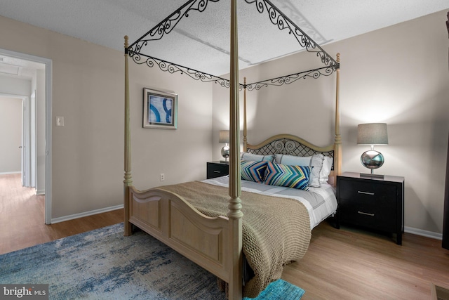 bedroom featuring a textured ceiling, baseboards, and wood finished floors
