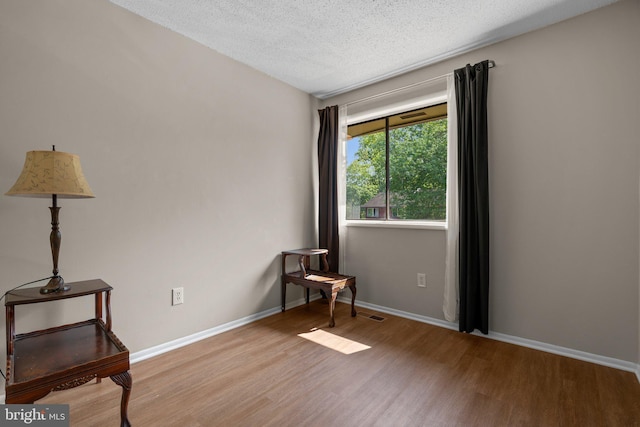 spare room with baseboards, a textured ceiling, and wood finished floors