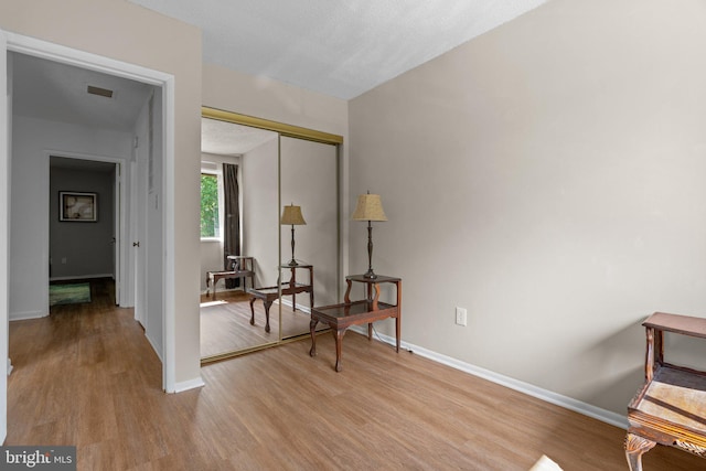 living area with baseboards, visible vents, and wood finished floors