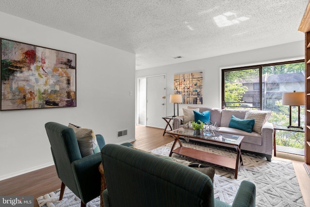 living area featuring visible vents, a textured ceiling, and wood finished floors