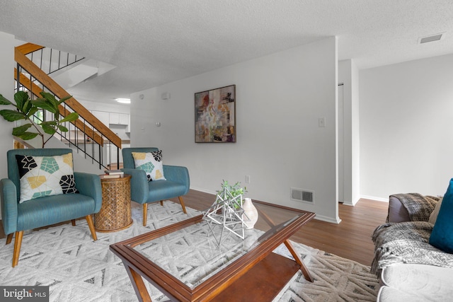 living area with stairway, baseboards, wood finished floors, and visible vents