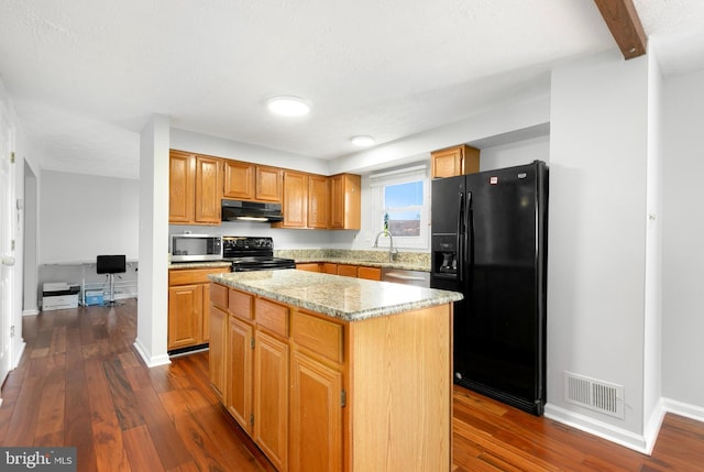 kitchen featuring visible vents, a sink, black appliances, under cabinet range hood, and dark wood-type flooring