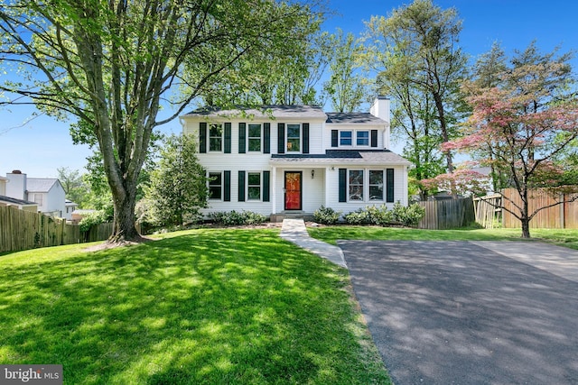 traditional home with fence, a chimney, and a front yard