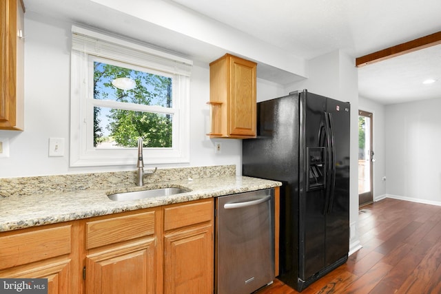 kitchen with light stone countertops, a sink, dishwasher, black refrigerator with ice dispenser, and dark wood finished floors