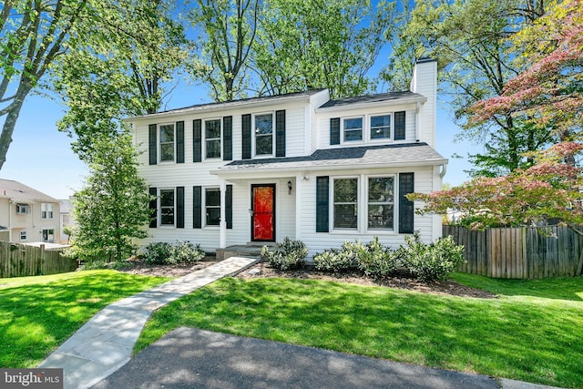 traditional home with fence, a front yard, and a chimney