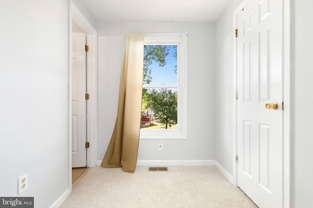 unfurnished bedroom with carpet floors, multiple windows, baseboards, and visible vents