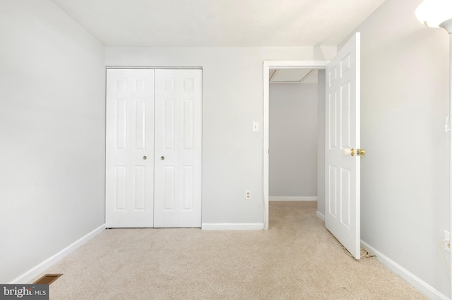 unfurnished bedroom with baseboards, light colored carpet, and a closet