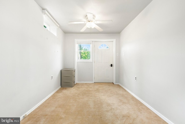 interior space with baseboards, ceiling fan, and light colored carpet