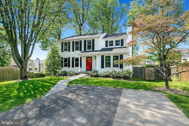 view of front of house featuring a front lawn, fence, and a chimney