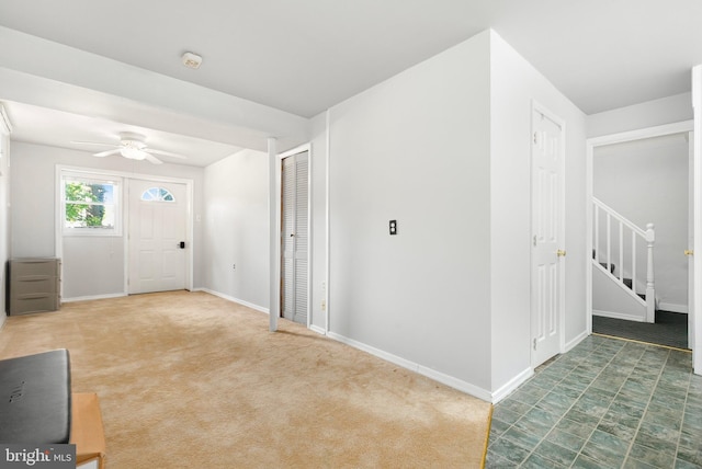 foyer entrance with stairs, a ceiling fan, and baseboards