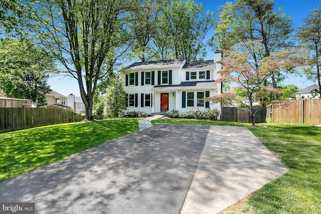 view of front of house with fence, a front yard, and a chimney