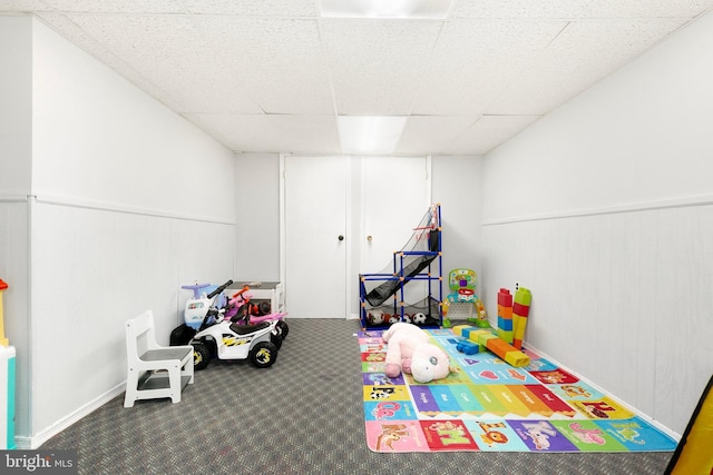 recreation room with baseboards, carpet flooring, a paneled ceiling, and a wainscoted wall