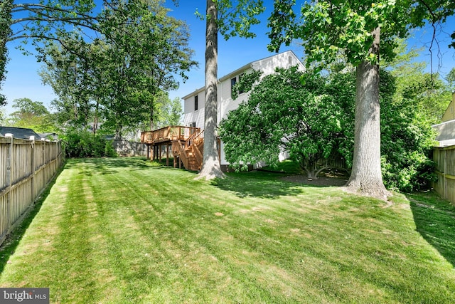 view of yard featuring a fenced backyard, a wooden deck, and stairway