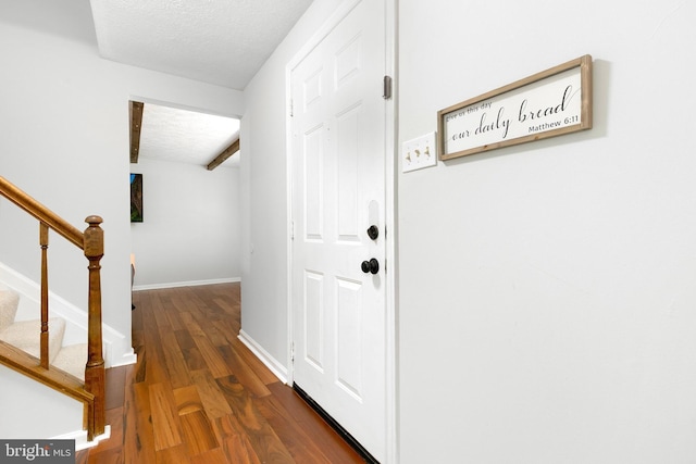 entryway with baseboards, stairs, a textured ceiling, and wood finished floors