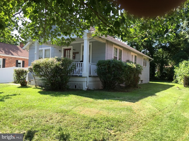 view of front facade featuring a porch, a front yard, crawl space, and fence