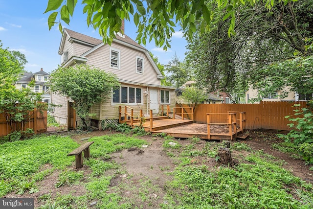 rear view of house with a wooden deck and fence