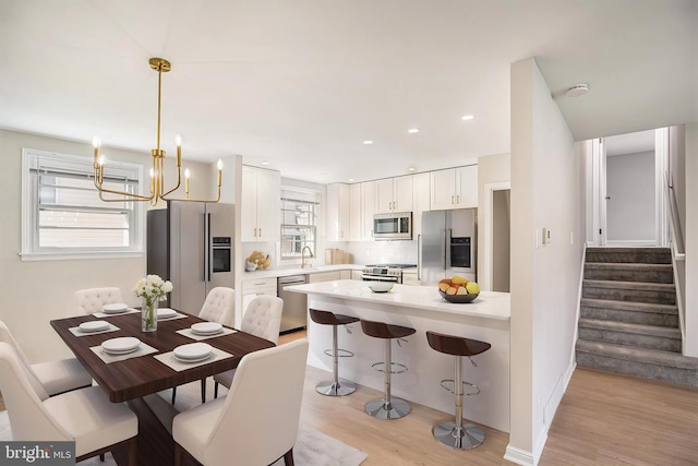 3839 Chalfont Dr, Philadelphia, PA 19154 - kitchen with light wood-type flooring, white cabinetry, a kitchen bar, light countertops, and appliances with stainless steel finishes