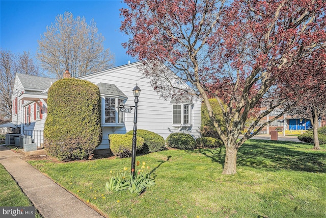 3839 Chalfont Dr, Philadelphia, PA 19154 - view of front facade featuring central air condition unit, roof with shingles, a chimney, and a front lawn