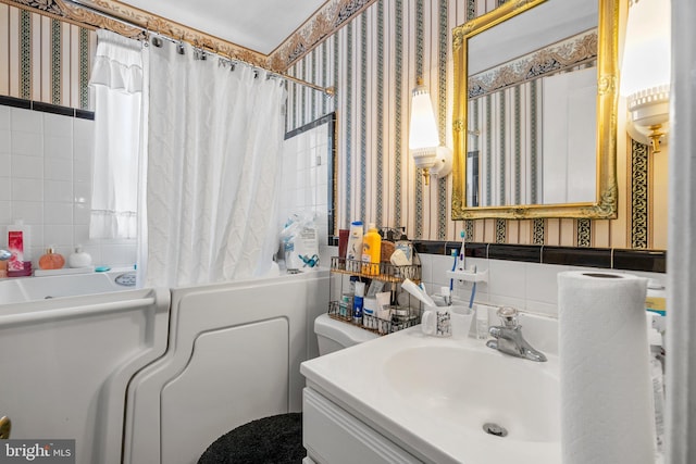 bathroom featuring wallpapered walls, toilet, tile walls, shower / bathtub combination with curtain, and vanity