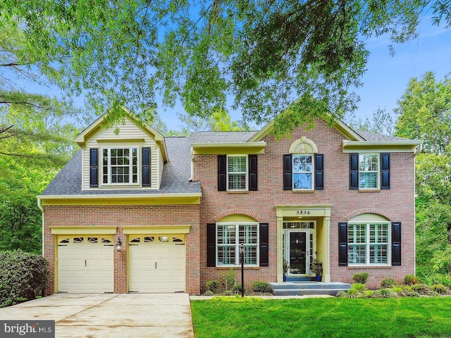 5856 Kittewan Ct, Manassas, VA 20112 - colonial house featuring concrete driveway, a garage, a front yard, and roof with shingles