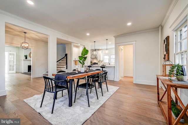 dining room featuring stairway, light wood-style flooring, baseboards, and crown molding