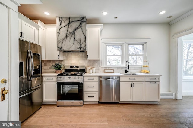 kitchen with a sink, tasteful backsplash, light countertops, and appliances with stainless steel finishes