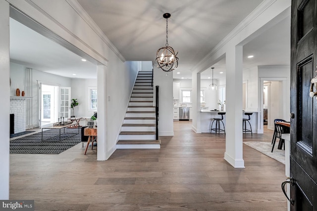 foyer featuring ornamental molding, plenty of natural light, a fireplace, stairs, and wood finished floors