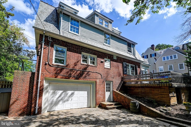 exterior space featuring an attached garage, aphalt driveway, and brick siding
