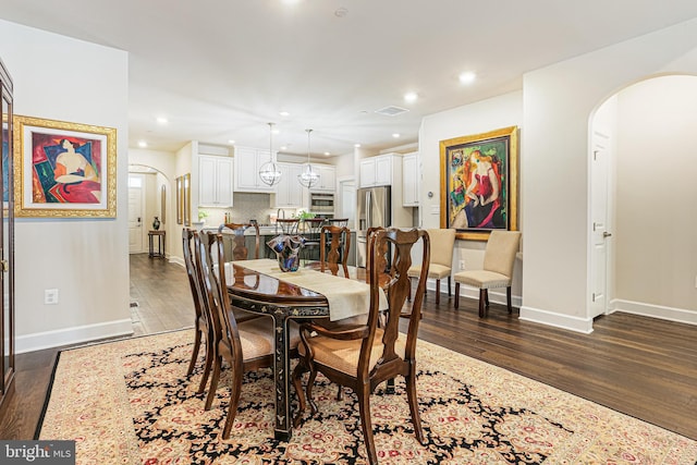 dining space with arched walkways, wood finished floors, and baseboards