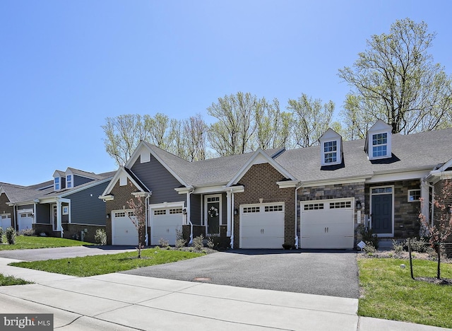 view of front of property featuring brick siding, an attached garage, aphalt driveway, and a front lawn