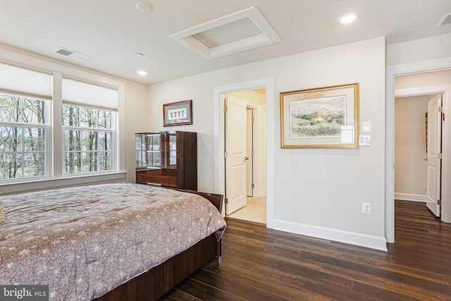 bedroom featuring attic access, baseboards, dark wood-type flooring, and visible vents